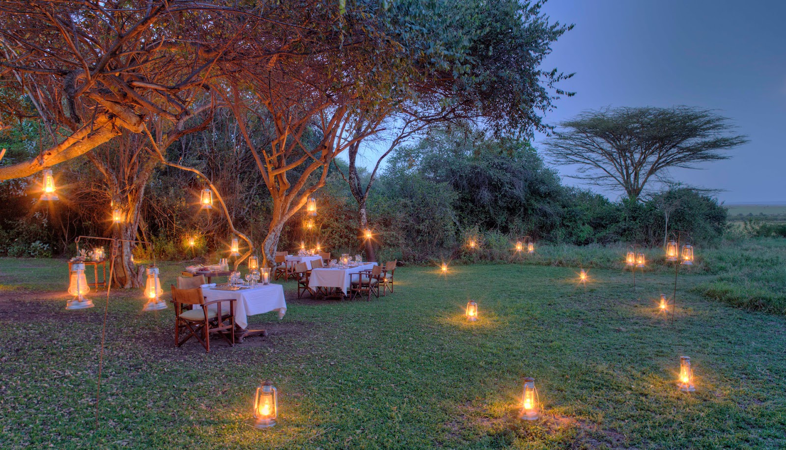 Lantern-lit bush dinner under trees at andBeyond Bateleur Camp on the Kichwa Tembo concession, Masai Mara, Kenya